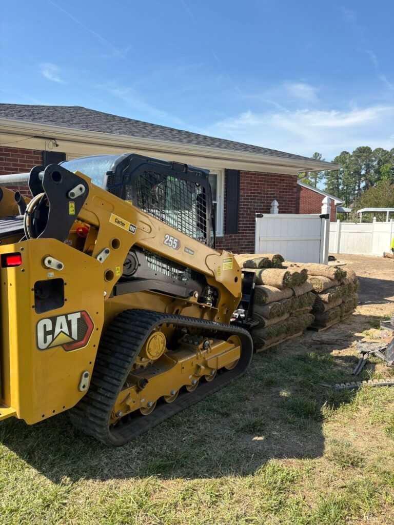 Skid steer grading near a brick home