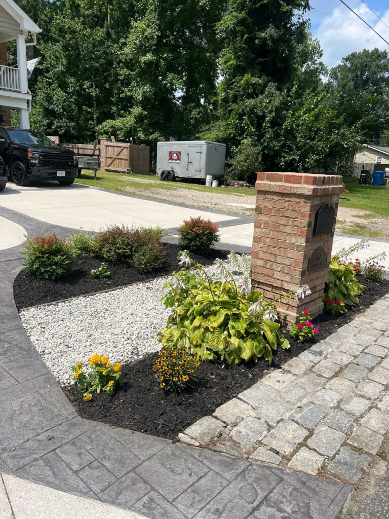 River rock and shrub bed with brick column