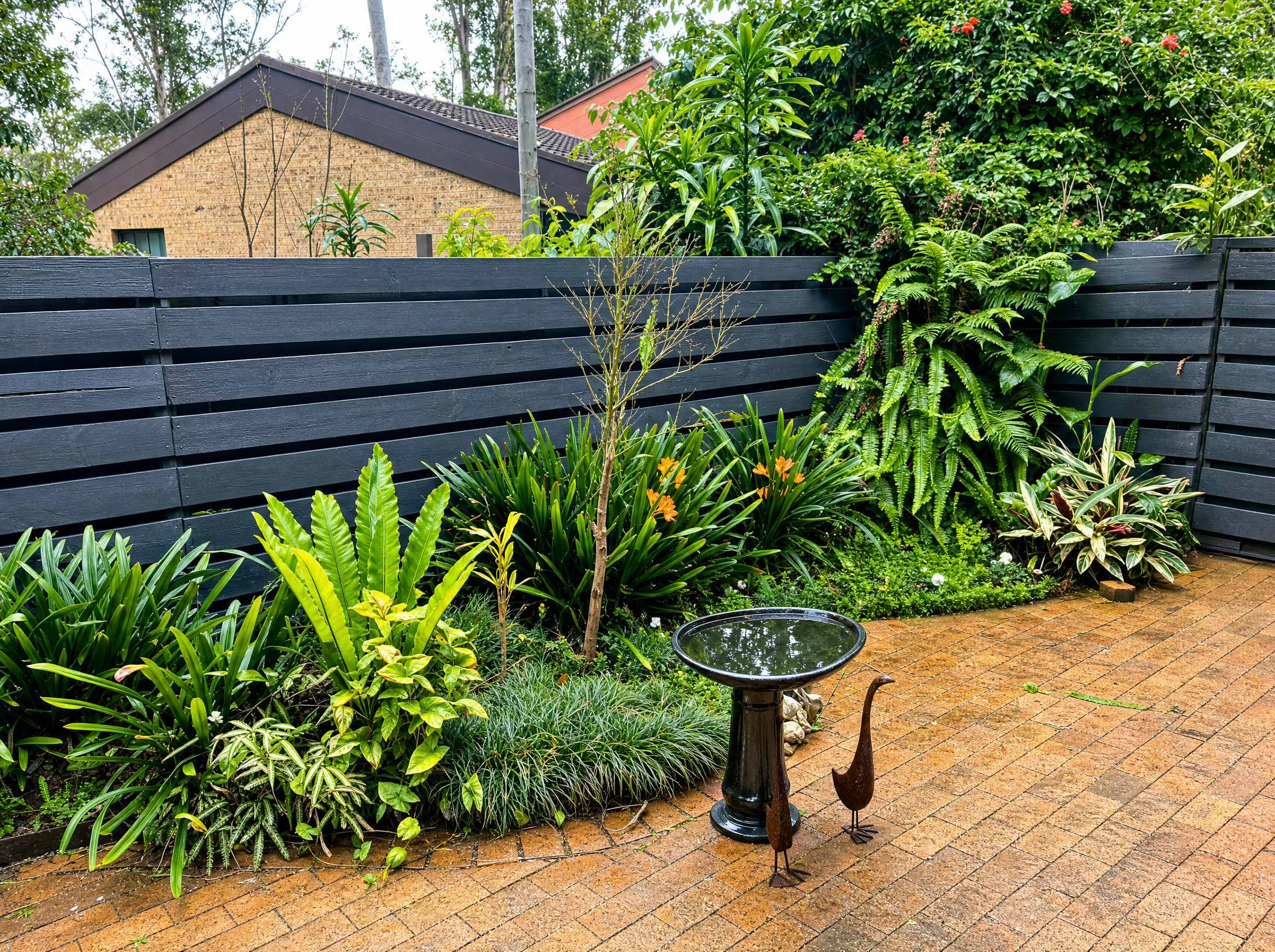 Backyard paver patio with horizontal privacy fence and plantings